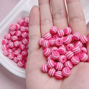Dettaglio di perline rotonde a strisce rosa e bianche per la creazione di gioielli fai da te