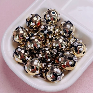 Detalle macro de cuentas doradas con patrones de cruz negra y puntos blancos para joyería DIY