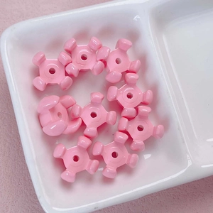 Cuentas de estrella acrílicas rosas para joyería DIY sobre una bandeja de cerámica