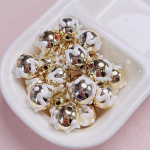 Detalle macro de cuentas doradas con diseño de esmalte blanco para hacer joyas DIY