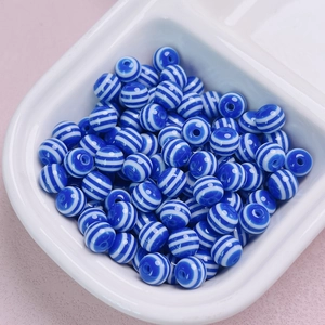 Dettaglio di perline tonde in resina a strisce blu e bianche per gioielli fai-da-te
