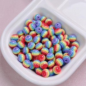 Dettaglio macro delle perline rotonde in resina a righe arcobaleno per gioielli fai da te