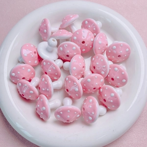 Macro shot of pink polka dot mushroom acrylic beads with pre-drilled holes for DIY jewelry
