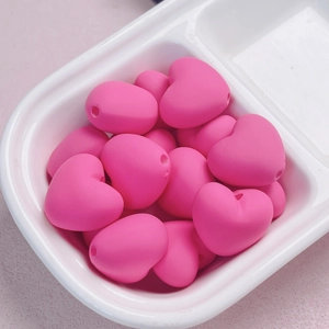 Makroaufnahme von matten rosa Acryl-Herzperlen mit glatter Oberfläche für DIY-Basteleien