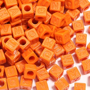 Vue macro des perles carrées orange vif en acrylique avec lettres pour la création de bijoux