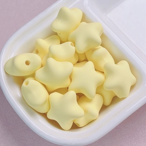 Macro shot of matte pastel yellow star and oval acrylic beads for DIY jewelry making