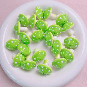 Detailed view of green mushroom acrylic beads with white dots in a white ceramic dish