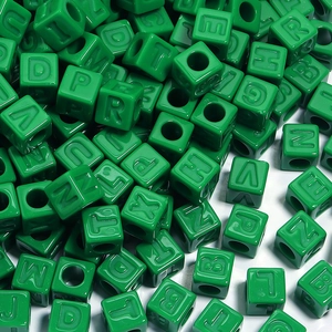 Vue macro de perles cubes alphabet en acrylique vert avec lettres gravées pour bijoux
