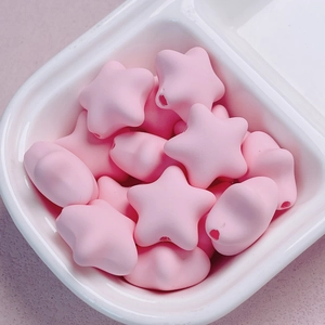 Detailed macro view of pink macaron star acrylic beads in a ceramic bowl for DIY crafts