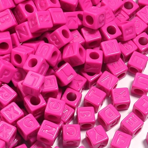Vue macro des perles carrées en acrylique fuchsia avec lettres pour bijoux DIY