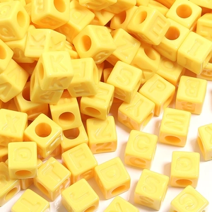 Vue macro de perles cubiques jaunes en acrylique avec lettres pour bijoux DIY