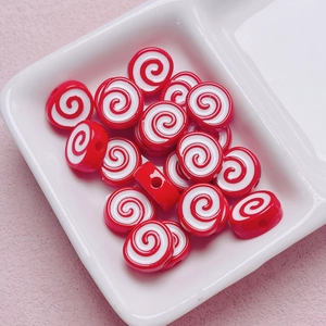 Macro shot of red and white spiral acrylic beads in a ceramic tray for DIY jewelry projects