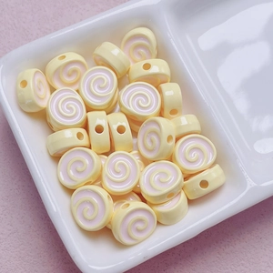 Macro shot of yellow acrylic spiral beads for DIY jewelry making in a white ceramic tray