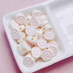 Macro shot of swirl pattern acrylic beads for DIY crafts in a white ceramic tray