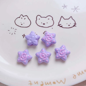 Close-up of five purple acrylic star beads with hand-painted pink spiral patterns