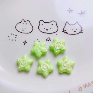 Detail of five green acrylic star beads with spiral patterns for DIY jewelry crafts