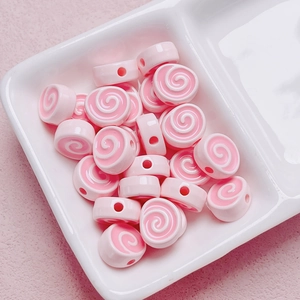 Macro view of pink and white spiral acrylic beads in a divider tray for DIY crafting