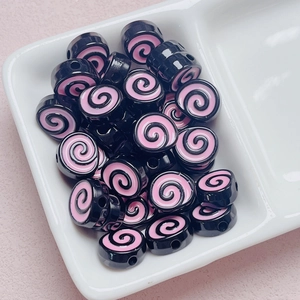 Close-up of black acrylic beads with pink spiral pattern for DIY jewelry crafts