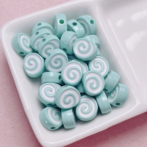 Macro shot of light blue and white spiral acrylic beads in a white ceramic dish