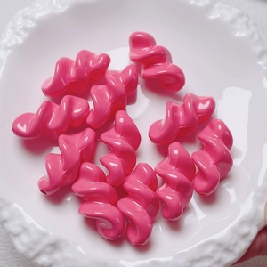 Detail of pink acrylic spiral beads with glossy finish on a decorative white porcelain plate