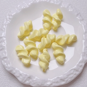 Close-up of cream spiral acrylic beads on white artistic tray for DIY jewelry projects