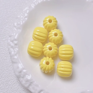 Macro shot of bright yellow pumpkin-shaped acrylic beads for DIY jewelry making and crafts