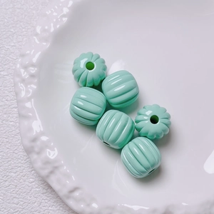 Close-up of mint green pumpkin acrylic beads on a white plate for DIY jewelry projects