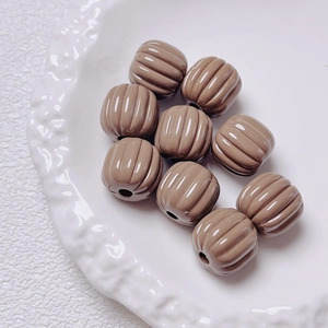 Macro detail of khaki pumpkin-shaped acrylic beads with ribbed texture for DIY crafts