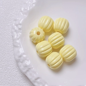 Macro shot of yellow pumpkin-shaped acrylic beads with center holes for DIY jewelry