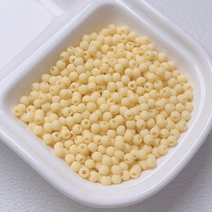 Macro view of 4mm matte cream rubberized beads for DIY jewelry making in a white box