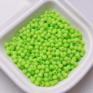 Macro shot of matte 4mm neon green spacer beads for DIY jewelry making in a white tray