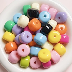 Macro shot of colorful acrylic barrel beads with glossy finish in a white ceramic bowl