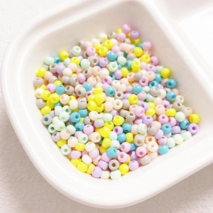 Macro shot of 4mm macaron mixed glass beads in a white container for DIY jewelry making