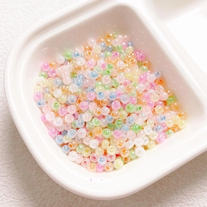 Macro shot of colorful 4mm macaron glass beads organized in a white plastic divider box