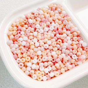 Macro detail of 4mm macaron mixed glass seed beads for DIY jewelry making in a white tray
