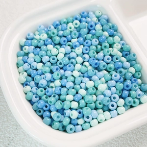 Macro detail of 4mm high-quality blue and green Czech glass seed beads in a white tray