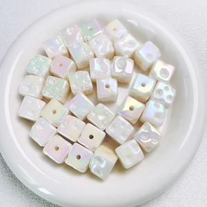 Close-up of Aurora cube spacer beads with pearlescent finish and star-engraved details