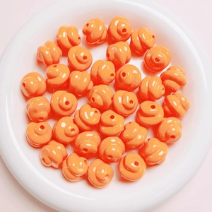Macro shot of orange glossy poop emoji loose beads for DIY craft jewelry making