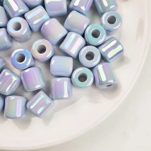 Close-up of iridescent cylinder acrylic beads in a white ceramic bowl for DIY jewelry