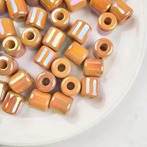 Close-up of orange-pink AB aurora coating cylindrical acrylic beads for DIY jewelry