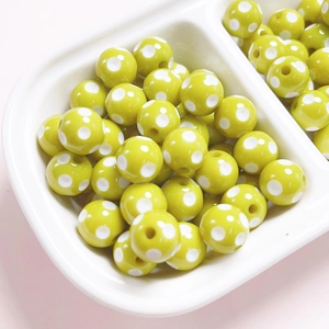 Detailed view of lime green resin beads with white polka dots for jewelry making