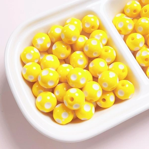 Macro shot of yellow 12mm resin beads with white polka dots for jewelry making