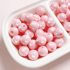 Macro detail of 12mm pink resin beads with white polka dots for DIY jewelry making