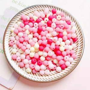 Mix of 6mm colorful matte acrylic round beads in a white ceramic dish for DIY crafts