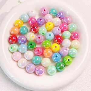 Macro shot of 14mm colorful UV coated acrylic shell beads in a ceramic tray for DIY craft