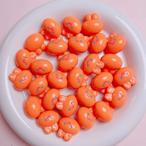 Close-up of 20mm orange acrylic bunny beads for DIY jewelry making in a ceramic dish