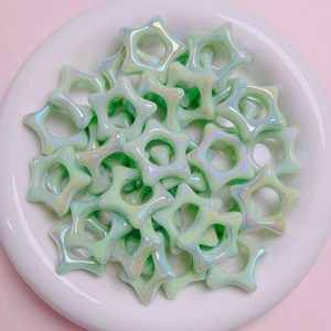 Dettaglio macro di perline acriliche a stella verde chiaro con riflessi iridescenti