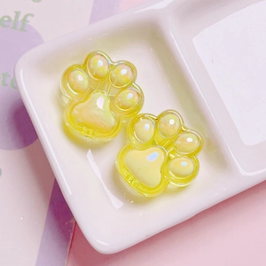 Detail of yellow cat paw acrylic beads with pearlescent finish in a ceramic dish