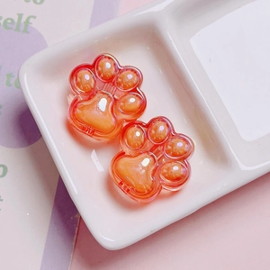 Macro detail of two orange acrylic cat paw charms for DIY phone chain accessories