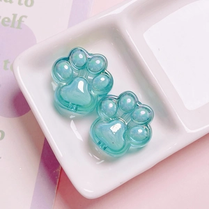 Macro shot of two pearlescent cat paw beads in pale green for DIY keychain making